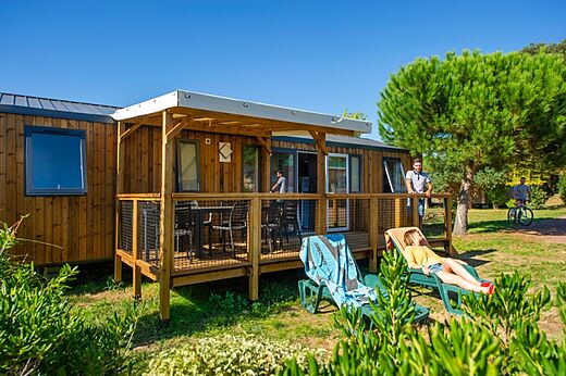 Mobil-home en bois avec terrasse couverte et chaises au camping CAPFUN Quatre Vents d'Oléron à St Georges d'Oléron (17).