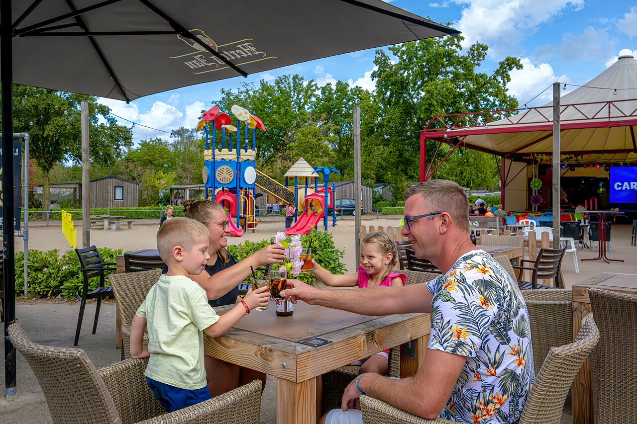 Familie st��t an nahe Spielplatz und Animationsb�hne auf Camping CAPFUN Rakelbos in Westelbeers.