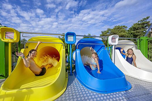 Kinder auf bunten Wasserrutschen im Camping CAPFUN Rakelbos in Westelbeers.