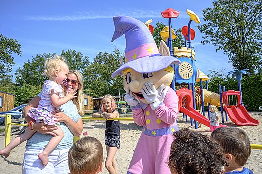 Maskottchen und lachende Kinder auf dem Spielplatz des Campingplatzes CAPFUN Rakelbos in Westelbeers.