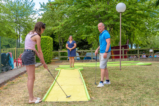 Famille jouant au mini-golf sur un parcours extérieur au camping CAPFUN Ranch des Volcans à Chatel-Guyon (63).