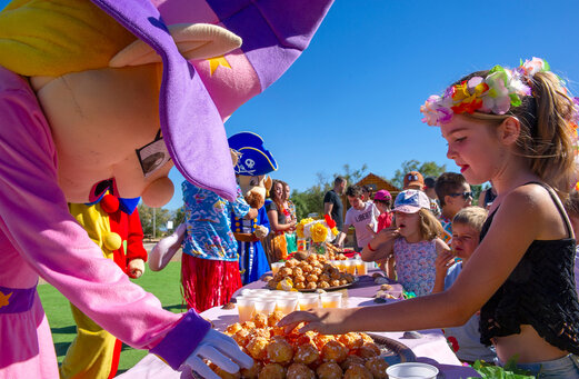 Mascottes et enfants joyeux autour d'un buffet de pâtisseries au camping CAPFUN Ranch des Volcans.