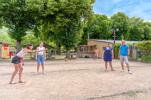 Jeunes et adultes jouant à la pétanque sur un terrain de sport au camping CAPFUN Ranch des Volcans à Chatel-Guyon (63).