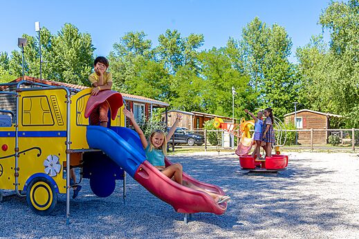 Bunter Spielplatz mit Rutsche und lachenden Kindern auf dem Campingplatz CAPFUN Régnière in VILLETTE D'ANTHON (38).
