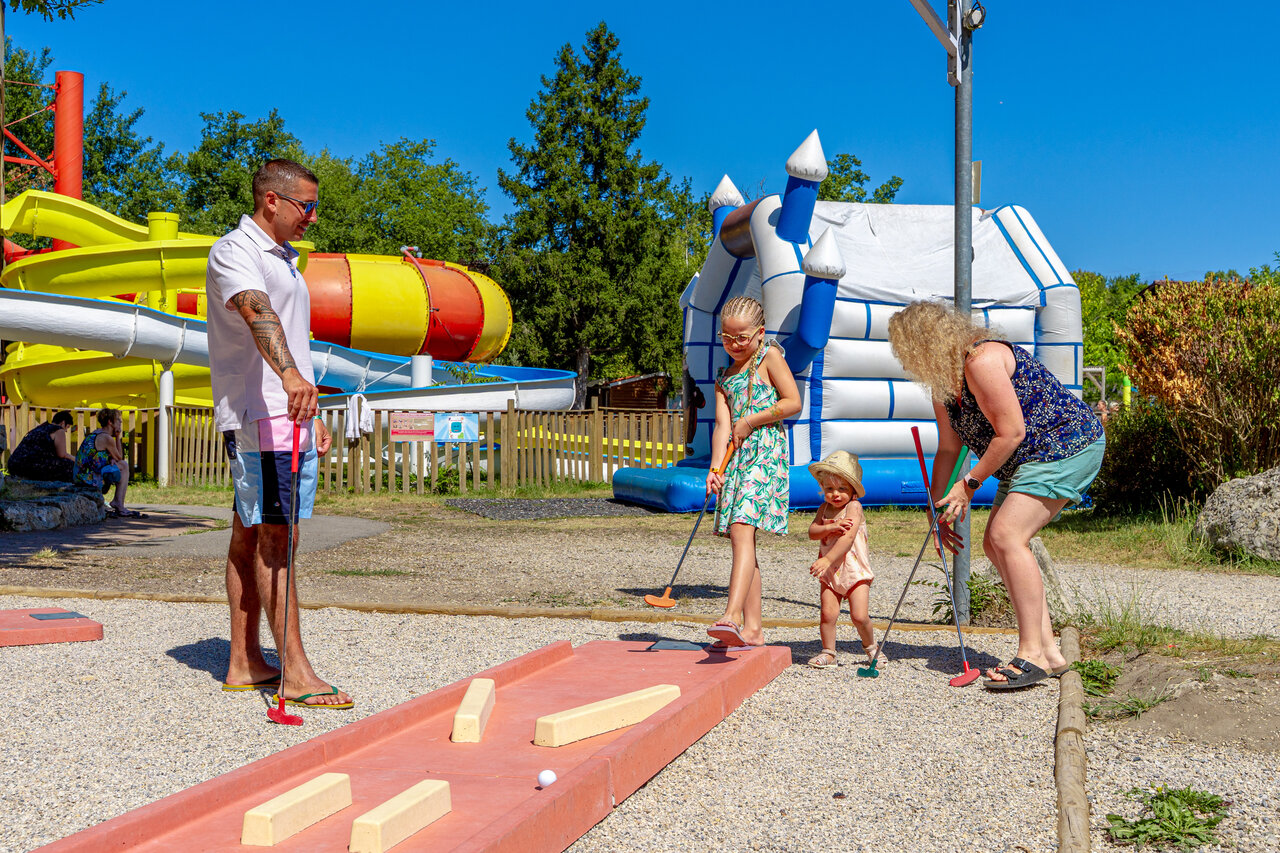 Familie spielt Minigolf mit Wasserrutschen auf dem Campingplatz CAPFUN R�gni�re in Villette d'Anthon.