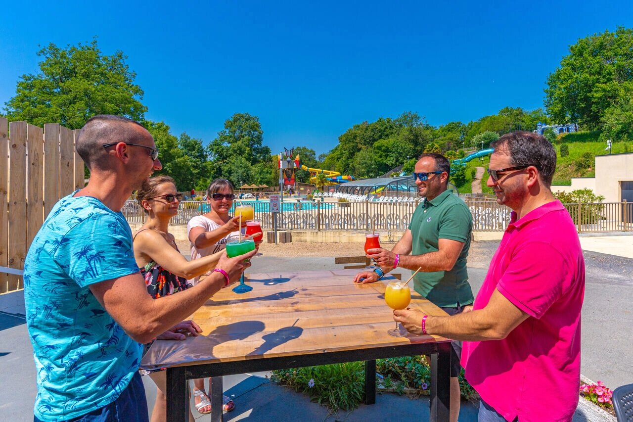 Friends toasting with cocktails at outdoor bar near pool CAPFUN La Rivi�re.