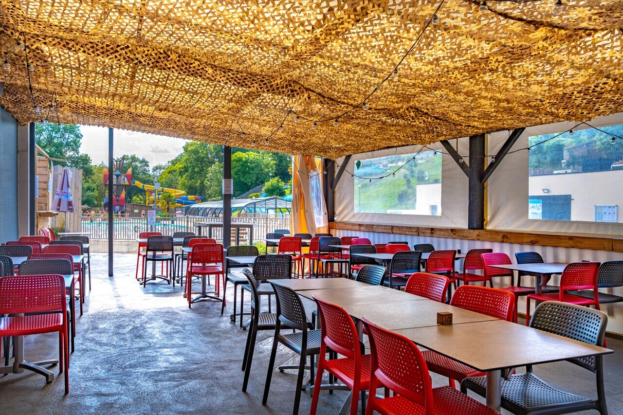 Shaded restaurant terrace, tables, chairs, pool, CAPFUN La Rivi�re campsite, Valence-en-Poitou (86).