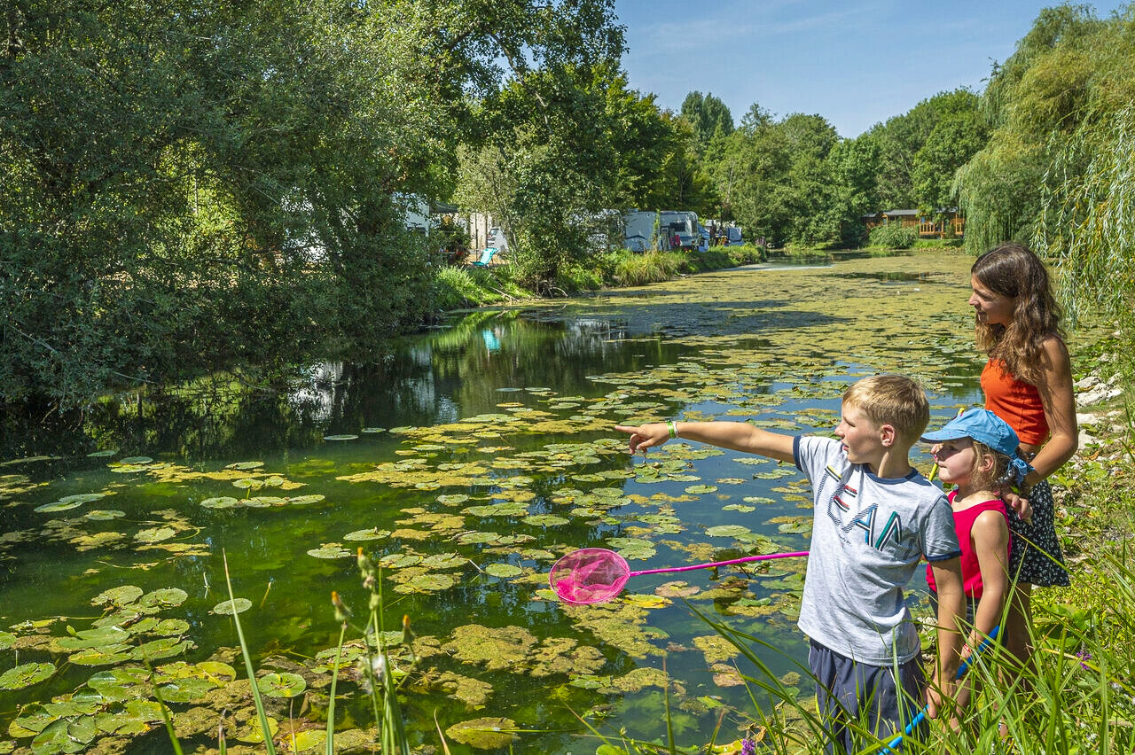 Children fishing natural river at CAPFUN La Rivi�re campsite in Valence-en-Poitou.