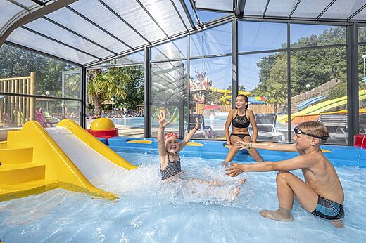 �berdachtes Schwimmbad, Rutsche, Kinder am Camping CAPFUN La Rivi�re, Valence-en-Poitou (86).