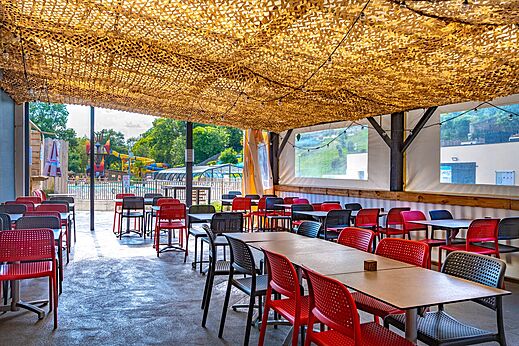 Schattiger Außenrestaurantbereich mit Tischen und Stühlen auf dem Campingplatz CAPFUN La Rivière in Valence-en-Poitou (86).