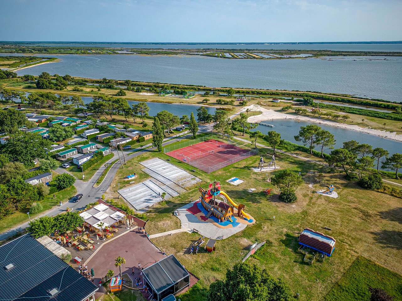 Mobile homes, playground, lake at CAPFUN Roumingue campsite in LANTON (33).