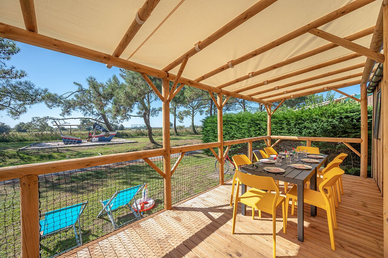 Mobile home terrace, table, chairs, playground at CAPFUN Roumingue campsite in LANTON (33).