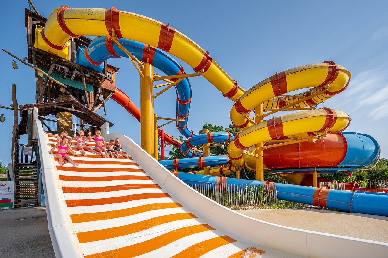 Colorful giant water slides and happy children at CAPFUN Roumingue campsite in LANTON (33).