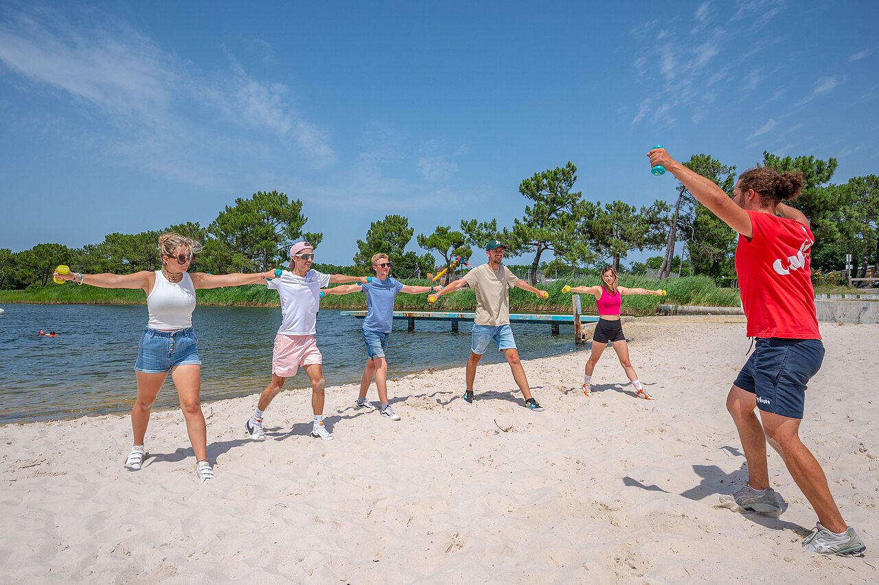Fitness animation on beach with weights at CAPFUN Roumingue campsite in LANTON (33).