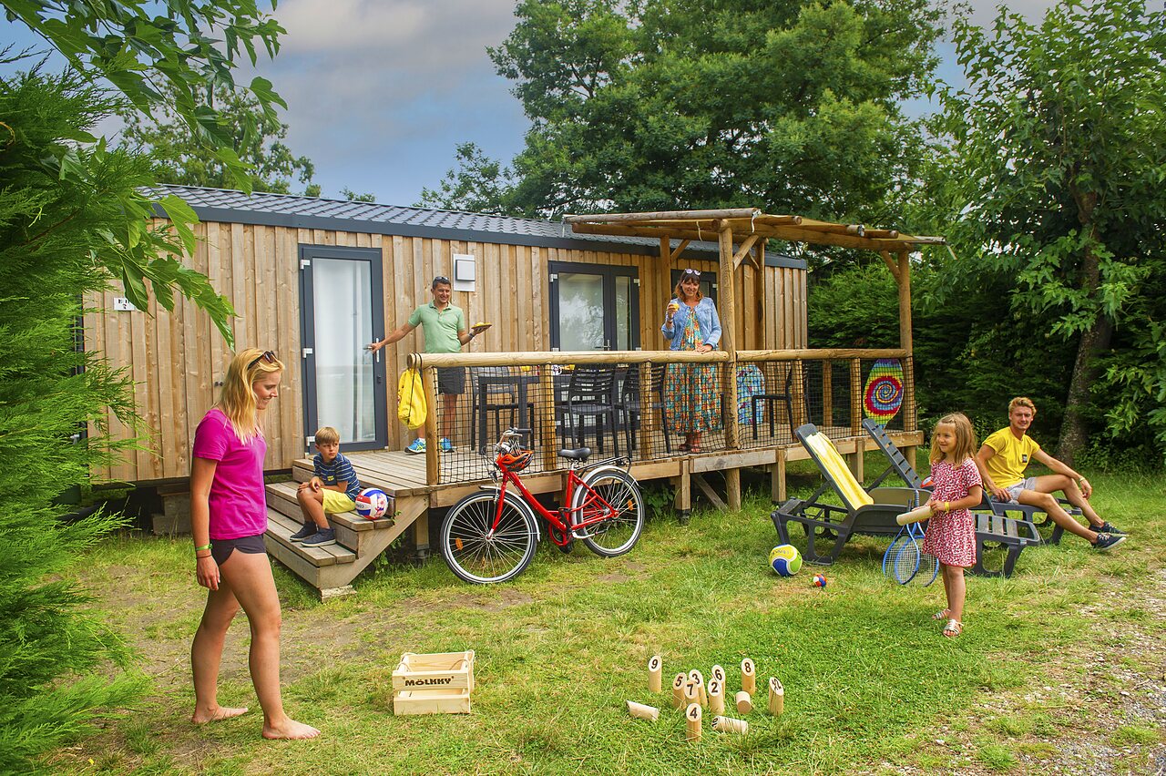 Family enjoying modern Mobil-home, deck and games at CAPFUN Roumingue campsite in LANTON (33).