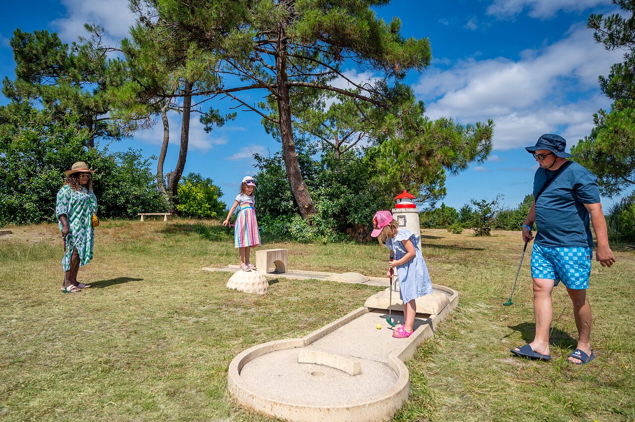 Family playing mini-golf on themed course at CAPFUN Roumingue campsite in LANTON (33).