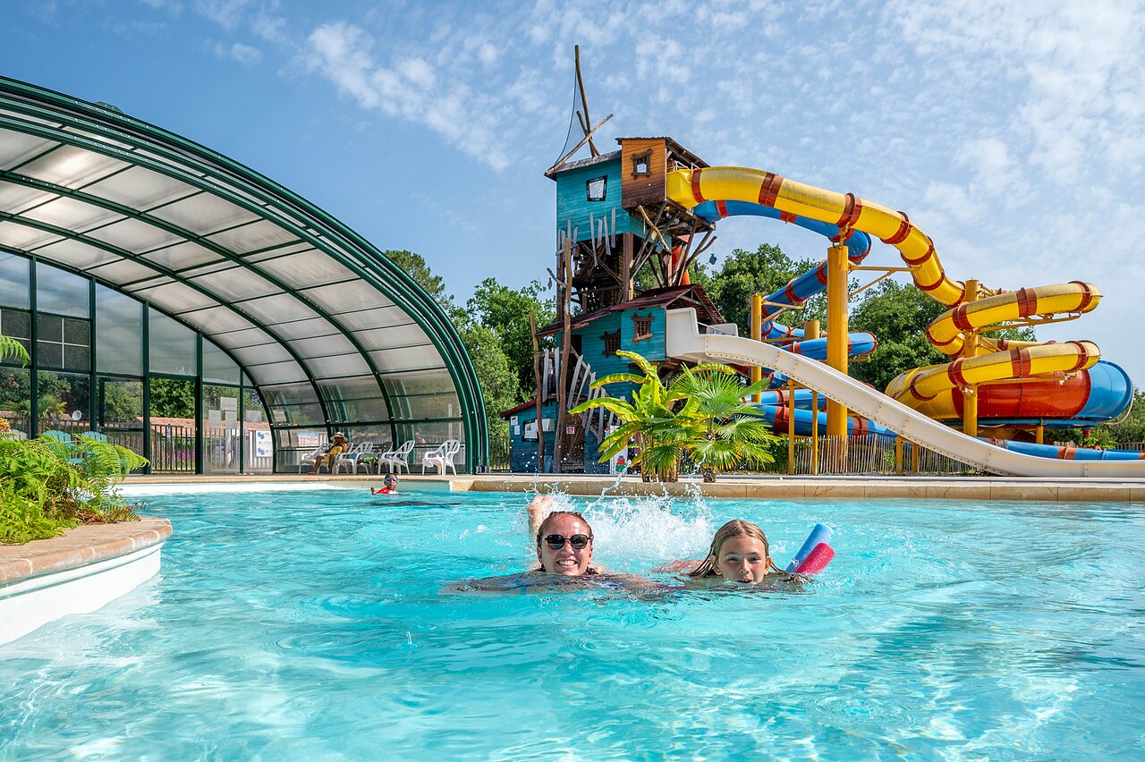 Outdoor swimming pool with water slides and play structure at CAPFUN Roumingue campsite in LANTON (33).