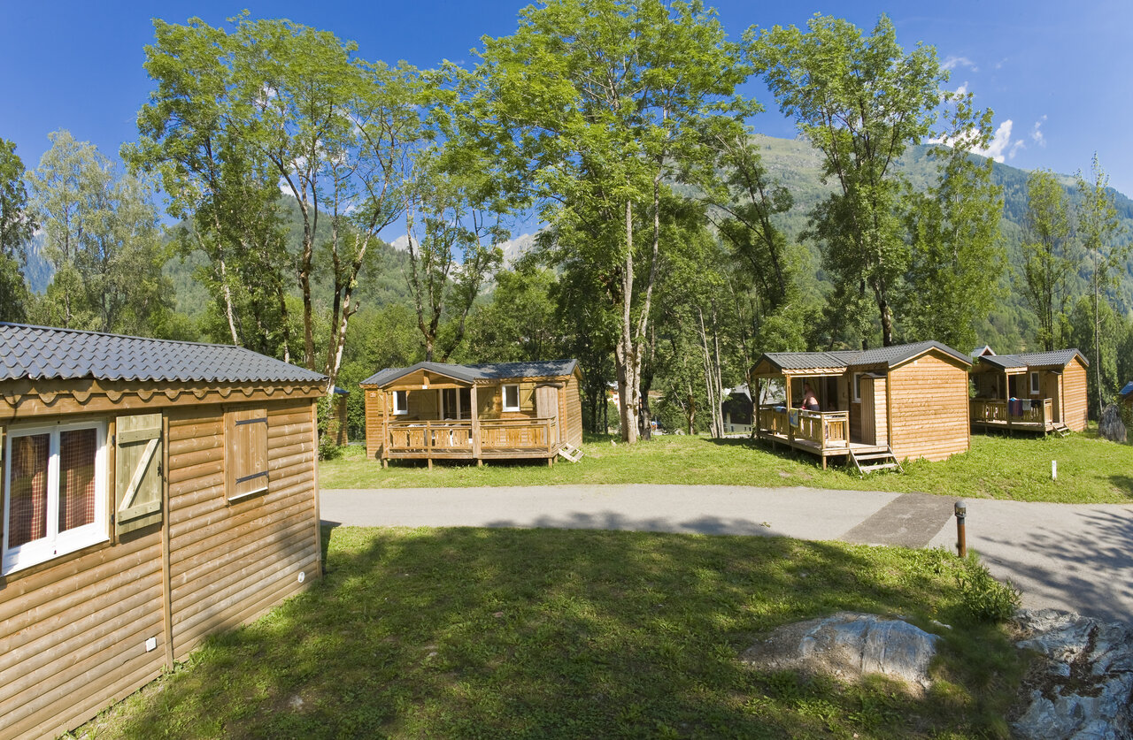 Houten Mobil-homes met terrassen, omringd door bomen op camping CAPFUN Saint Colomban.