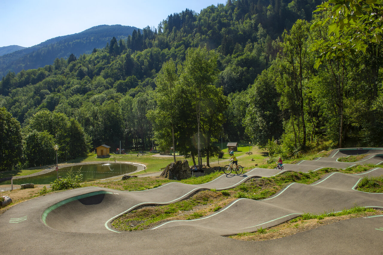 Pumptrack en fietsende kinderen bij het meer op camping CAPFUN Saint Colomban.