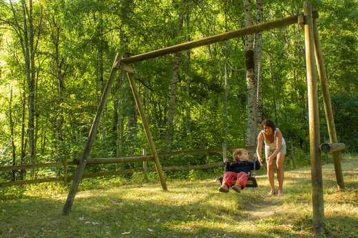 Kind auf Holzschaukel mit Frau am Campingplatz CAPFUN Saint Colomban in Saint Colomban des Villards (73).