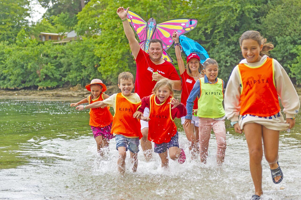 Kinderen en animatoren spelen in het water met een vlieger op camping CAPFUN Saint Laurent in LA FORET FOUESNANT (29).