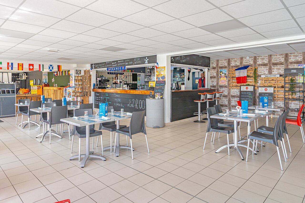 Bar und Restaurantbereich mit Tischen und St�hlen auf dem Campingplatz CAPFUN Saint Laurent in LA FORET FOUESNANT (29).