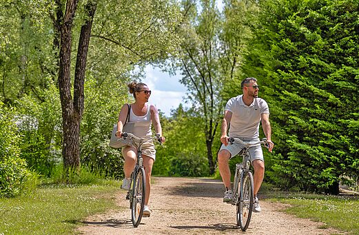 Couple à vélo sur chemin verdoyant au camping CLICOCHIC Les Saules de Cheverny.