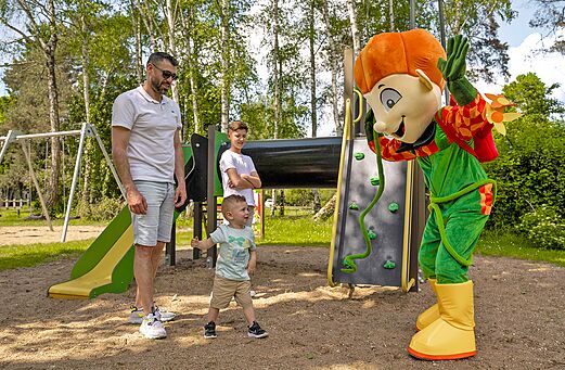 Mascotte et enfants sur l'aire de jeux au camping Les Saules de Cheverny.