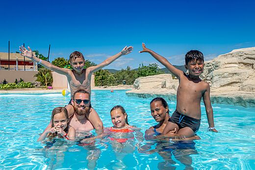 Famille souriante profitant de la piscine extérieure au camping VAGUES OCEANES Soleil de Provence.