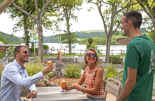 Clients souriants profitant de boissons rafra�chissantes sur la terrasse du bar au camping CLICOCHIC Soleil Levant � Canet-de-Salars (12).
