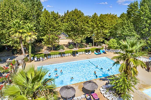 Buitenzwembad met zwemmers en stoelen op camping CAPFUN Soubeyranne in REMOULINS (30).