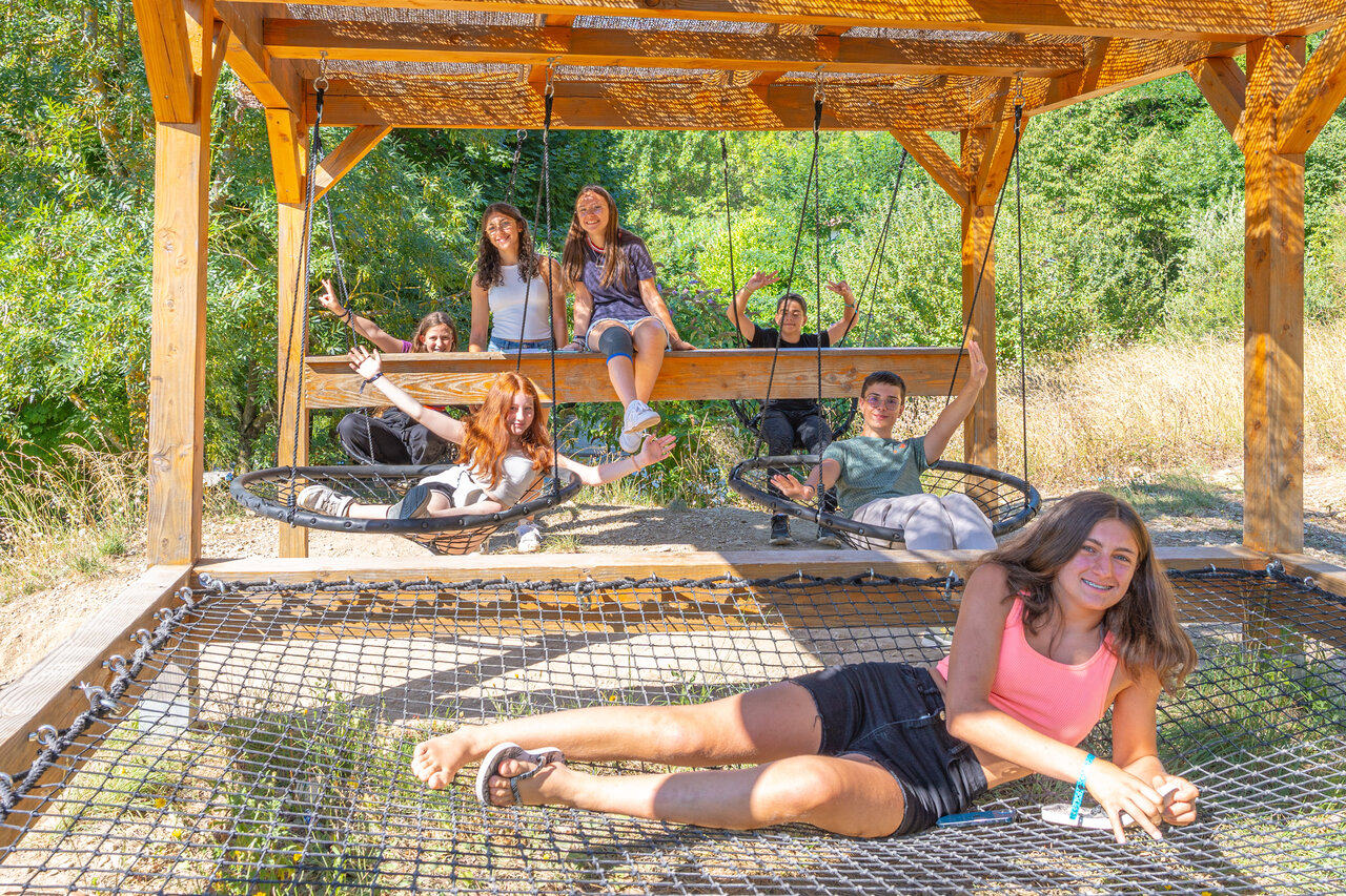 Jongeren op schommels en speelnet op camping CLICOCHIC Source du Jabron in Comps (26).