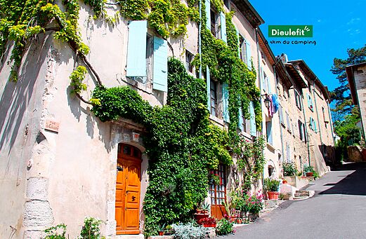Blumengeschmückte Straße und alte, mit Efeu bewachsene Häuser in Dieulefit, Drôme Provençale.