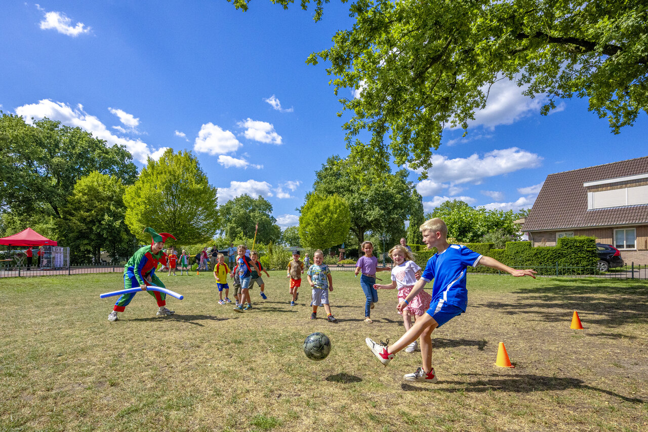 Kinder spielen Fu�ball mit verkleidetem Animateur auf Camping CAPFUN De Sprookjescamping in Rheeze.
