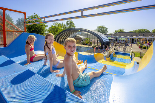 Riesenwasserrutsche und lachende Kinder auf dem Campingplatz CAPFUN De Sprookjescamping in Rheeze.