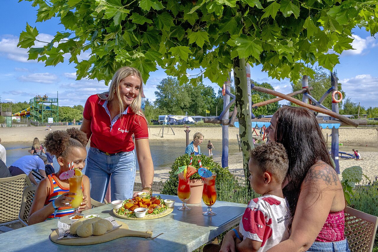 Essen auf Terrasse, Strand und Wasserrutschen im CAPFUN Vakantiepark Capfun het Stoetenslagh.
