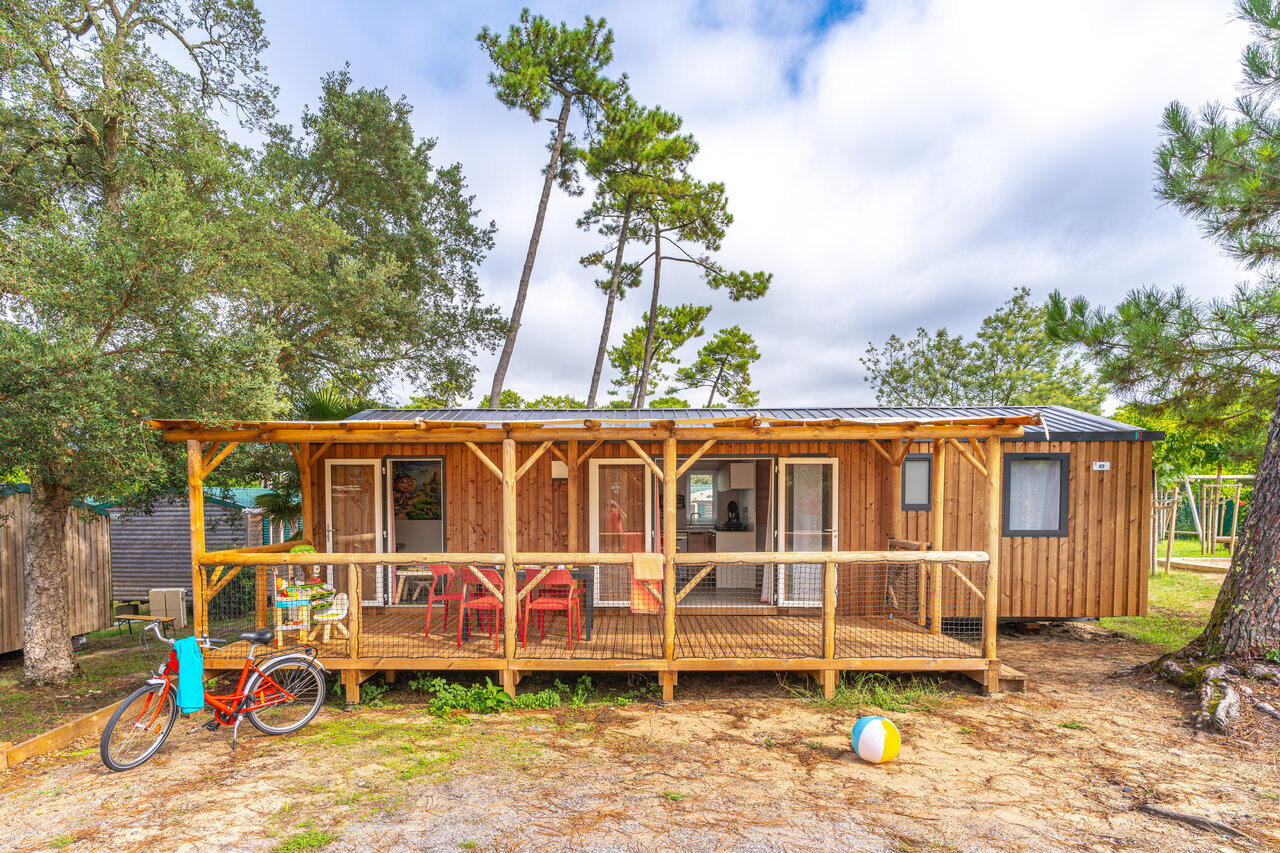 Wooden mobile home with terrace, bicycle, natural ambiance at CAPFUN Sud Land campsite.