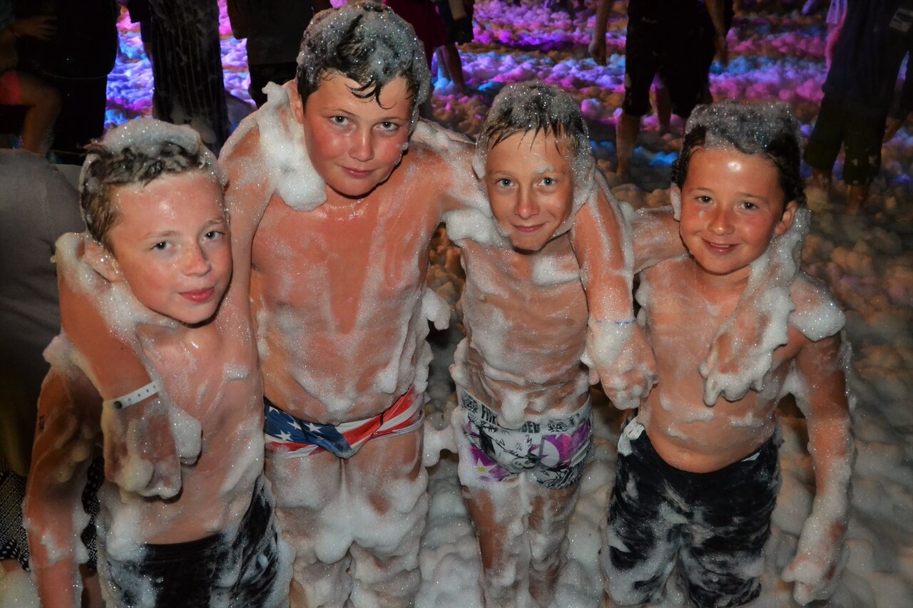 Smiling children enjoying a lively foam party at CAPFUN Sud Land campsite in Labenne-Ocean.