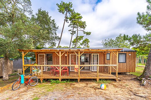 Holz-Mobilheim mit überdachter Terrasse und Fahrrad auf dem Campingplatz CAPFUN Sud Land in Labenne-Ocean (40).