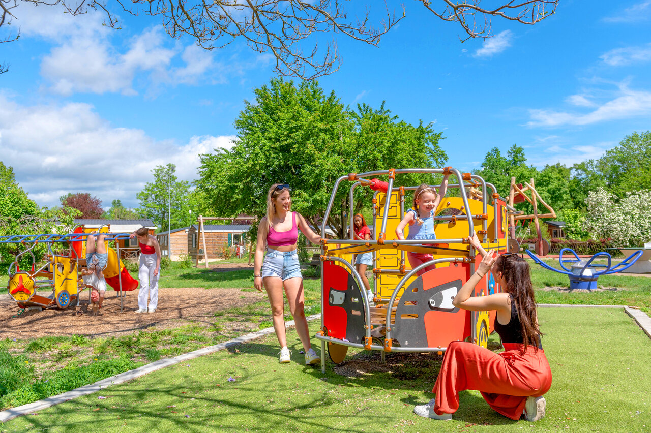 Farbenfroher Spielplatz mit Kindern und Erwachsenen auf dem Campingplatz CAPFUN Suzel in Sainte-Croix-en-Plaine (68).