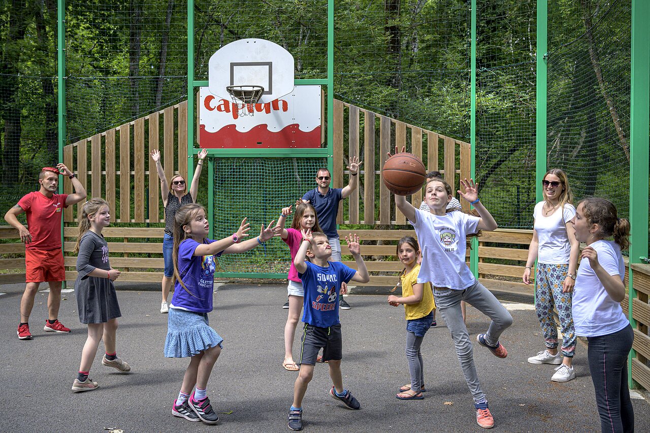 Basketball court with children and adults playing at CAPFUN Talaris Vacances campsite in Lacanau (33).