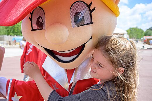 Enfant câlinant la mascotte du camping CAPFUN Talaris Vacances à Lacanau (33).
