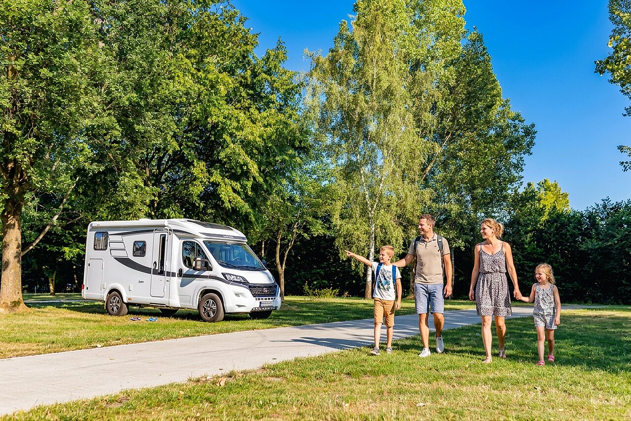 Familie und wei�es Wohnmobil auf gr�nem Stellplatz auf dem Campingplatz CAPFUN Tecklenburg in Tecklenburg-Leeden (49).