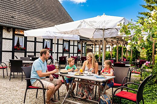 Familie isst auf der Restaurantterrasse auf dem Campingplatz CAPFUN Tecklenburg in Tecklenburg-Leeden (49).