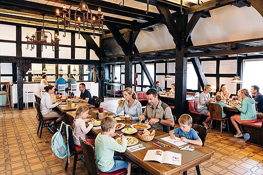 Familles et couples dînant dans le restaurant rustique du camping CAPFUN Tecklenburg à Tecklenburg-Leeden (49).