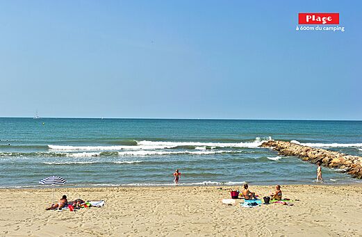 Zandstrand met zee, golven en zwemmers op camping CAPFUN Teorix in MARSEILLAN PLAGE (34).