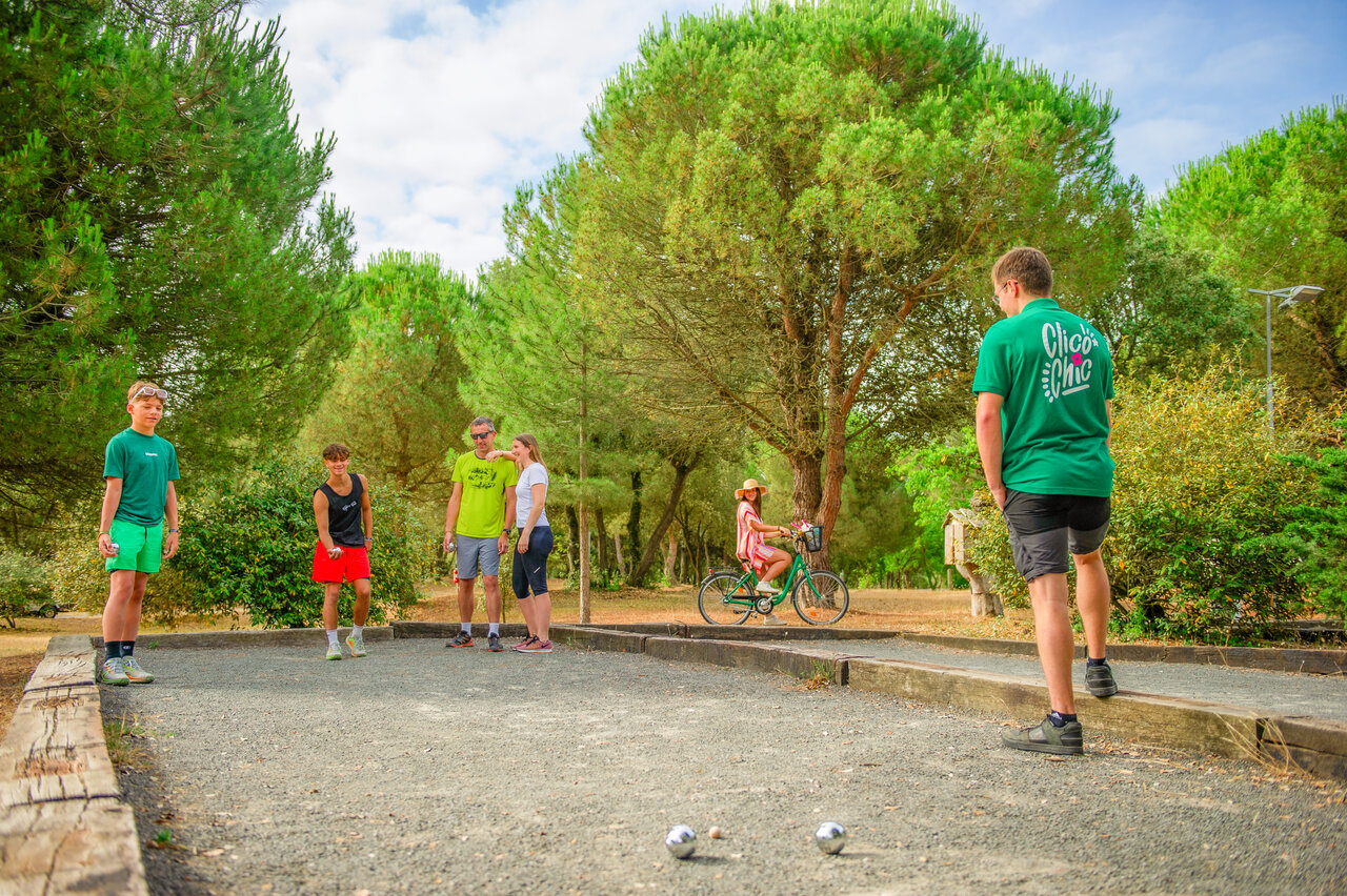 Familie und Freunde spielen Boule auf dem Campingplatz CLICOCHIC Plage des Tonnelles.
