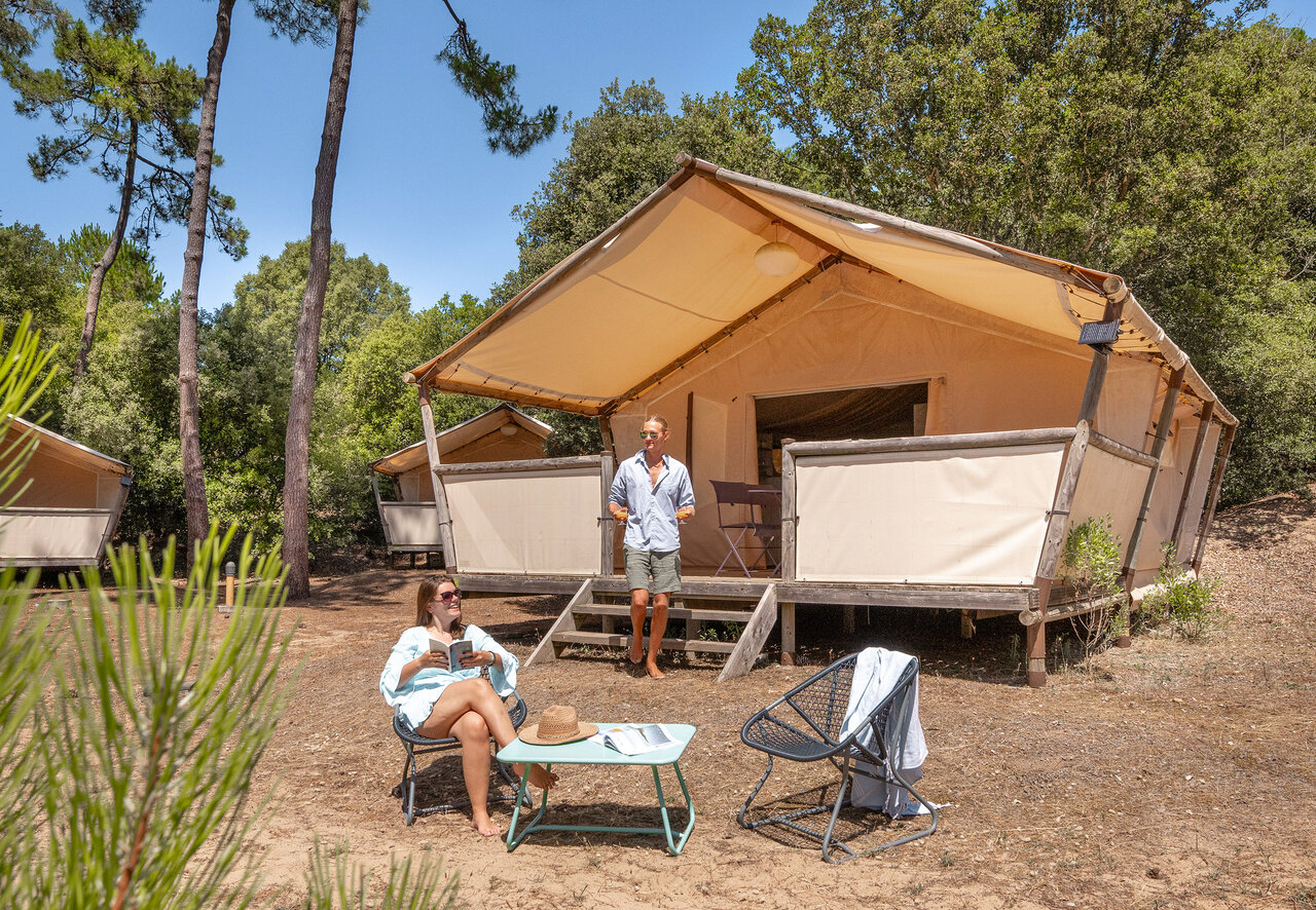Entspanntes Paar vor Glamping-Lodgezelt auf Camping CLICOCHIC Plage des Tonnelles (85).