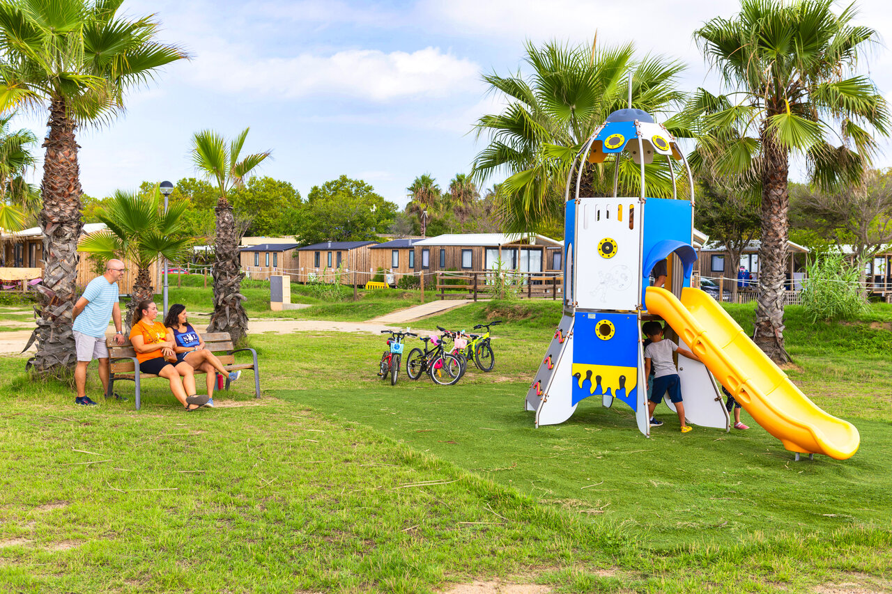 Raketen-Spielplatz mit Rutsche, Kindern und Mobilheimen auf dem Campingplatz CAPFUN Tordera-Nacions in Malgrat de Mar.