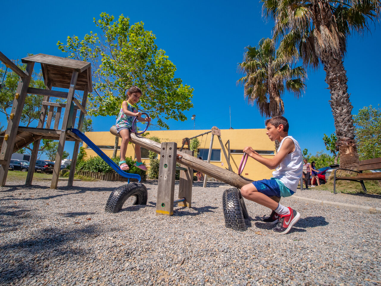 Spielplatz mit Kindern auf Wippe auf dem Campingplatz CAPFUN Tordera-Nacions in Malgrat de Mar.
